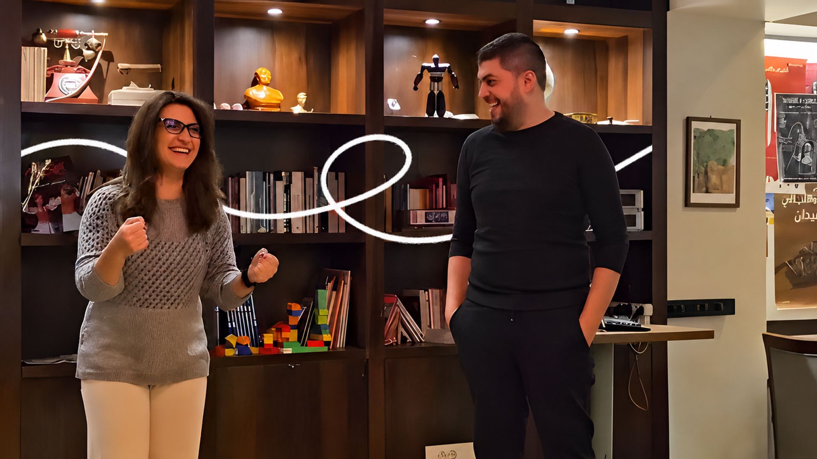 A woman and a man signing in a room lined with bookshelves